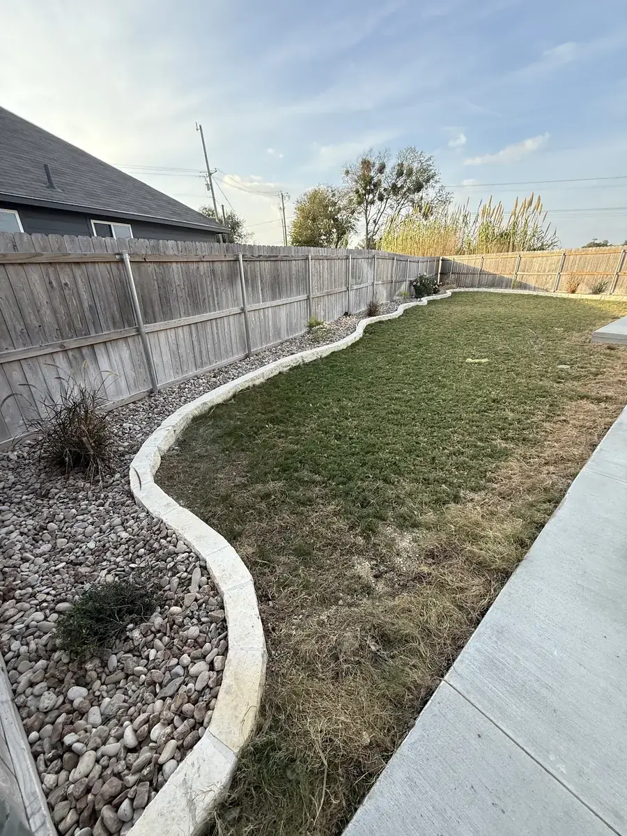 Concrete landscape curbing separating fresh sod from a rock bed in Temple, Texas